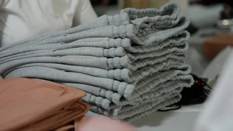 Sweatpants are ready for packaging and sale. Pile of folded gray sweatpants in Stock Footage 274655659