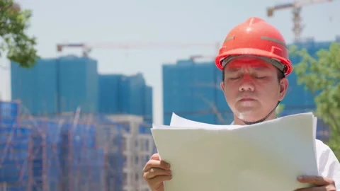 Sweaty construction engineer with safety helmet checks construction blueprints 動画素材 336346729