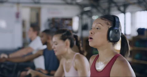 Sweaty female athlete drinking water inside a busy gym during her workout. Tired Stock Footage