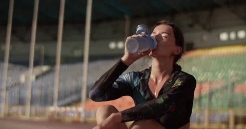 Sweaty sprinter drinking water after working out at stadium Stock Footage 243626591