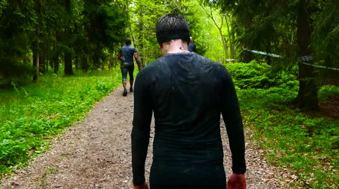 SWEDEN: Camera moving behind a muddy tired male young athlete in jungle Stock Footage 63378373