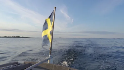 Swedish flag waving in the wind at the rear of a boat traveling the sea Stock Footage 159093100