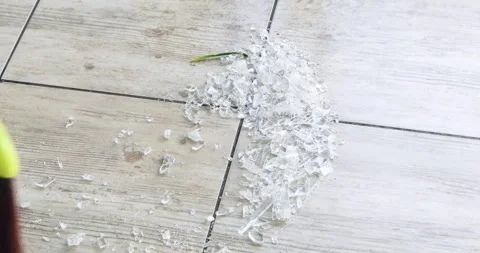 Sweep small pieces of broken glass from kitchen tiles with a broom to avoid  Stock Footage 334168245