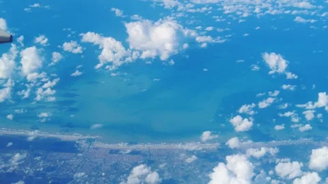 Sweep wing plane air thick clouds below land towns sides ocean meeting horizon Stock Footage 320845816