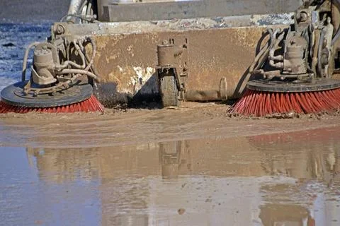 Sweeper machine dragging mud from a street, produced by a flood Stock Photos