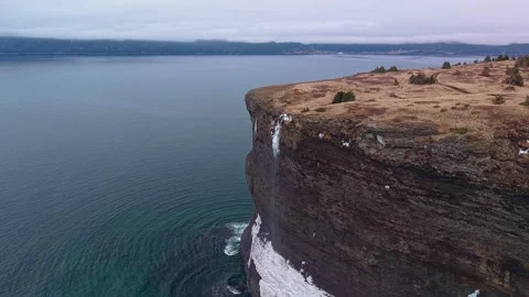 Sweeping aerial drone view of sheer coastal cliffs with frozen waterfall Vidéo 334157609