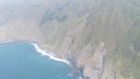 A sweeping aerial shot captures the dramatic cliffs and rugged coastline around Stock Footage 346680181