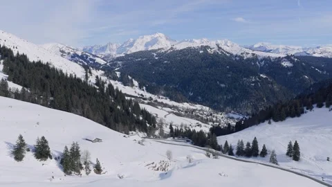 A sweeping aerial shot captures the snow-covered landscape of the Col des Aravis Stock Footage 346664860