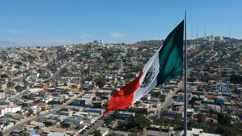 Sweeping aerial shot of the Mexican flag waving over Tijuana. Stock Footage