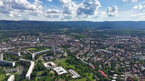 Sweeping aerial view of dense city in lush valley with high rise blocks, parks, Stock-Footage 342358588