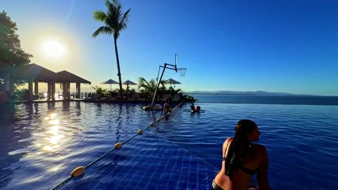 Sweeping camera movement across a stunning tropical pool with sunset ocean Stock Footage 334162458