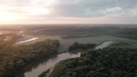 Sweeping drone footage showcases a river surrounded by expansive rural Vídeos de archivo 345083890