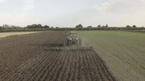 Sweeping drone shot of tractor plowing field Stockbeeldmateriaal 251840994