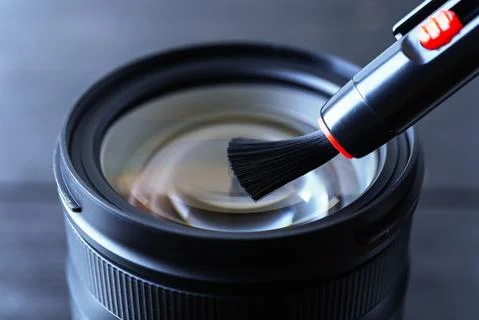 Sweeping dust from front lens using lens pen brush. Routine removal of dust. Stock Photos
