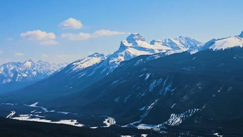 A sweeping mountain landscape rises beyond a vast evergreen forest and winding 動画素材 334105721