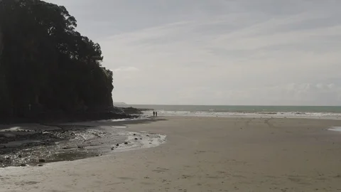 Sweeping orbit low-to-high from sandy beach to majestic clifftop house Stock Footage 113899172