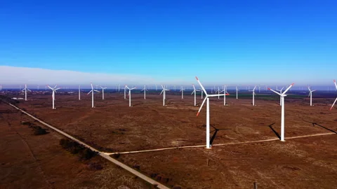 Sweeping row of wind turbines across dry grassland, Bulgaria Stockbeeldmateriaal 341763035