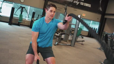 Sweeping Shot of Man Working Out With Battle Ropes at Gym | Slow Motion Stock Footage 167284678