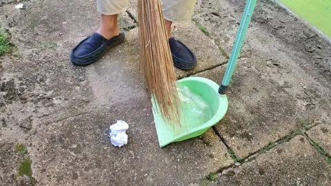 Sweeping up trash using a broom and dustpan in the yard Stock Footage 322903511