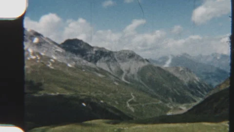 Sweeping View Of Alpine Mountains And Verdant Hills Under Cloudy Sky Stock Footage 322132593
