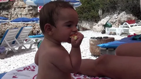Sweet baby eats apple at the beach, Crystal child Stock Footage 39912527
