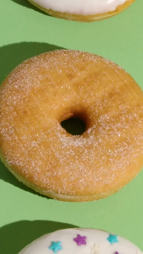 Sweet baked sugar donuts moving upwards over green background 库存影片 331781237