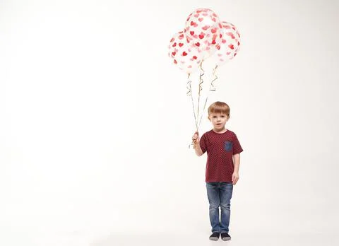 Sweet boy holding balloons with red and pink hearts. Valentines day or kids Stock Photos