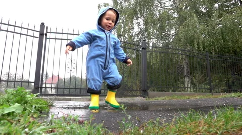Sweet boy is playing in puddle, slow motion Stock Footage 67689440