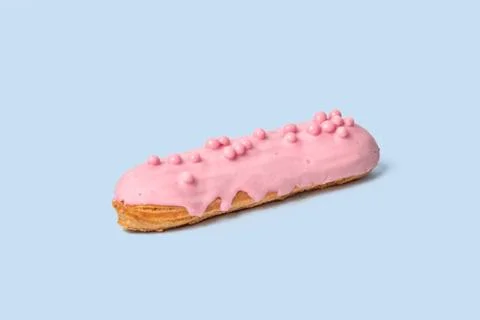 A sweet Breakfast. Bright Eclair in pink glaze sprinkled with pink jelly beans. Stock Photos