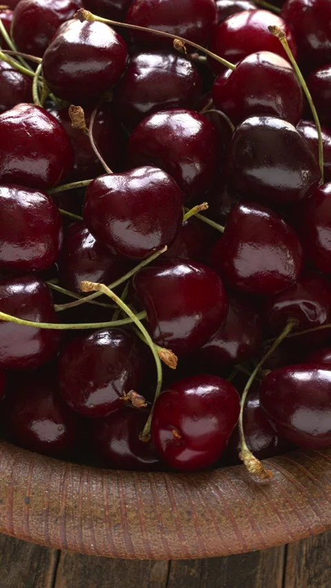 Sweet cherries with stems rotating close up on handmade dish, vertical video. Video stock 345006884