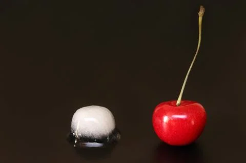 Sweet cherry and  ice cube on black background Stock Photos