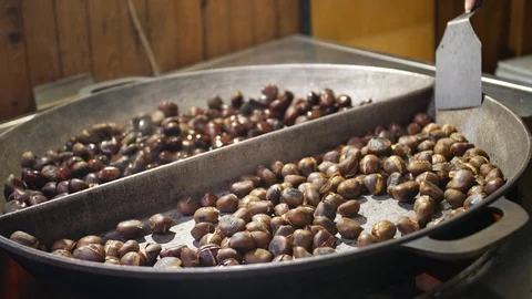 Sweet chestnuts roasted on big pan, hand stirs them up Stock Footage 99635521