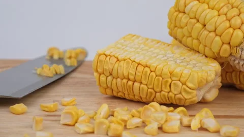 Sweet corn kernels are cut from the cob on a wooden cutting board with a knife. Stock Footage 243629975