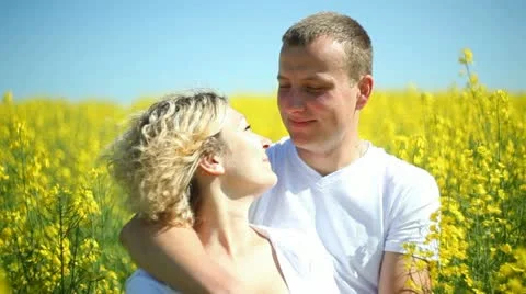 Sweet couple in a field of rape Stock Footage 11110480