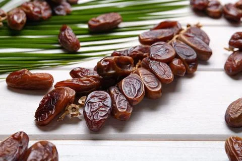 Sweet dried dates with palm leaf on white wooden table, closeup 스톡 사진