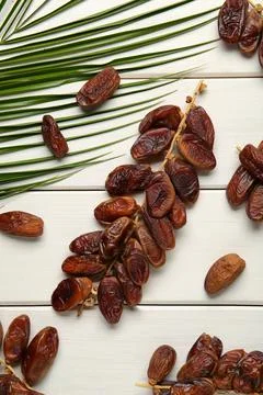Sweet dried dates with palm leaf on white wooden table, flat lay 스톡 사진