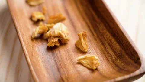 Sweet dried pineapple slices falling on a wooden bowl Stock Footage 271230700