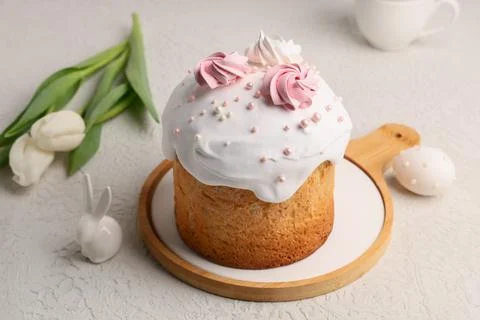 Sweet Easter cake with meringue, egg, toy bunny and tulip flowers on white ba Stock Photos
