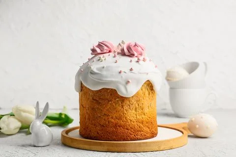 Sweet Easter cake with meringue, egg, toy bunny and tulip flowers on white ba Stock Photos