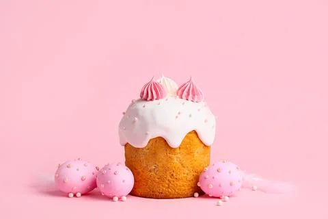 Sweet Easter cake with meringue, feathers and painted eggs on pink background Stock Photos