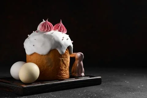 Sweet Easter cake with meringue, painted eggs and toy bunny on black backgrou Stock Photos