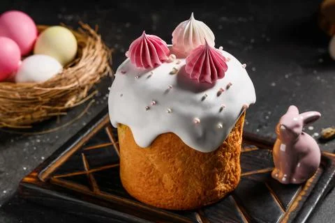 Sweet Easter cake with meringue, painted eggs and toy bunny on black backgrou Stock Photos