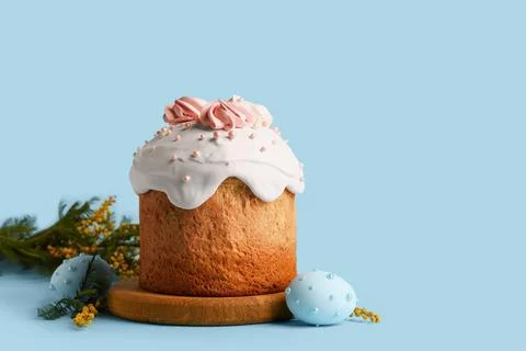 Sweet Easter cake with meringue, painted eggs and mimosa flowers on blue back Stock Photos
