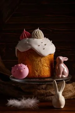 Sweet Easter cake with meringue, painted egg and toy bunnies on wooden backgr Stock Photos