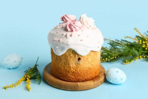 Sweet Easter cake with meringue, painted eggs and mimosa flowers on blue back Stock Photos