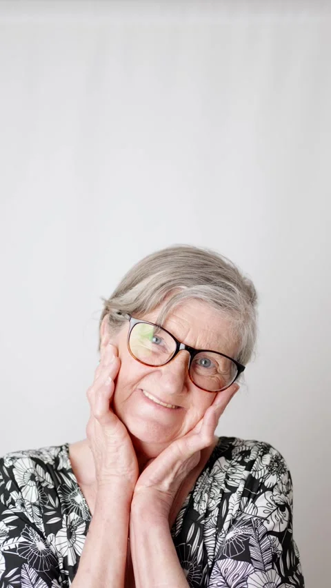 Sweet expression of and old lady smiling at camera and holding her cheeks Stock Footage 285636880