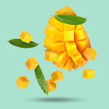 Sweet fresh mango cut in cubes falling on turquoise background Stock Photos