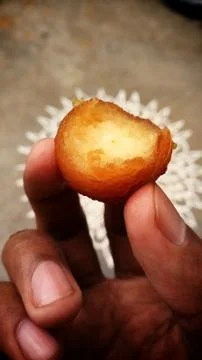 A sweet Gulab jamun captured while eating with his hand Stock Photos