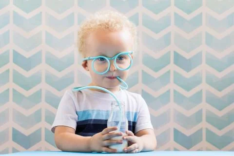 Sweet little boy drinking milk with funny glasses straw. Growing up concept. Stock-Fotos