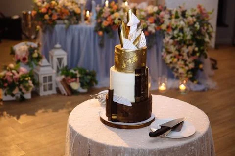 A sweet multi-level decorated cake stands on the table. Bouquet on the Stock Photos